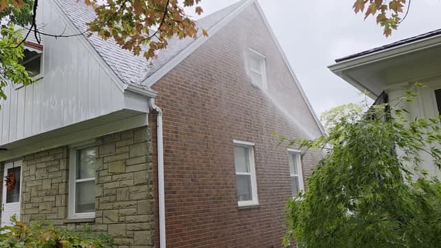 Soft washing the brick gable of a house